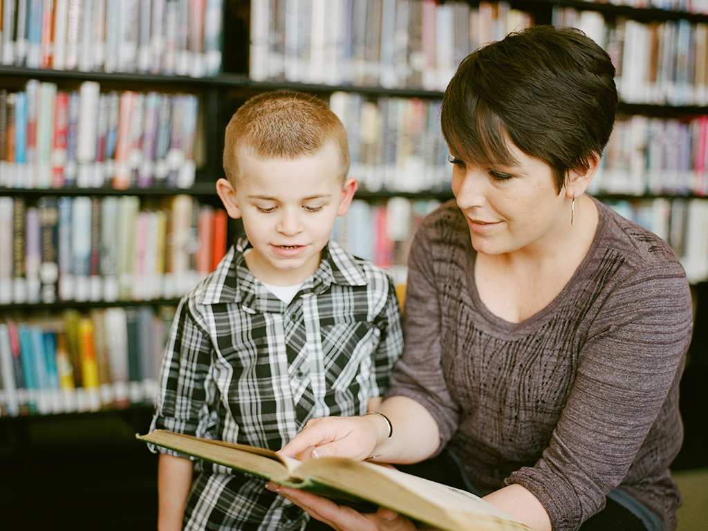 An adult and a child reading a book together